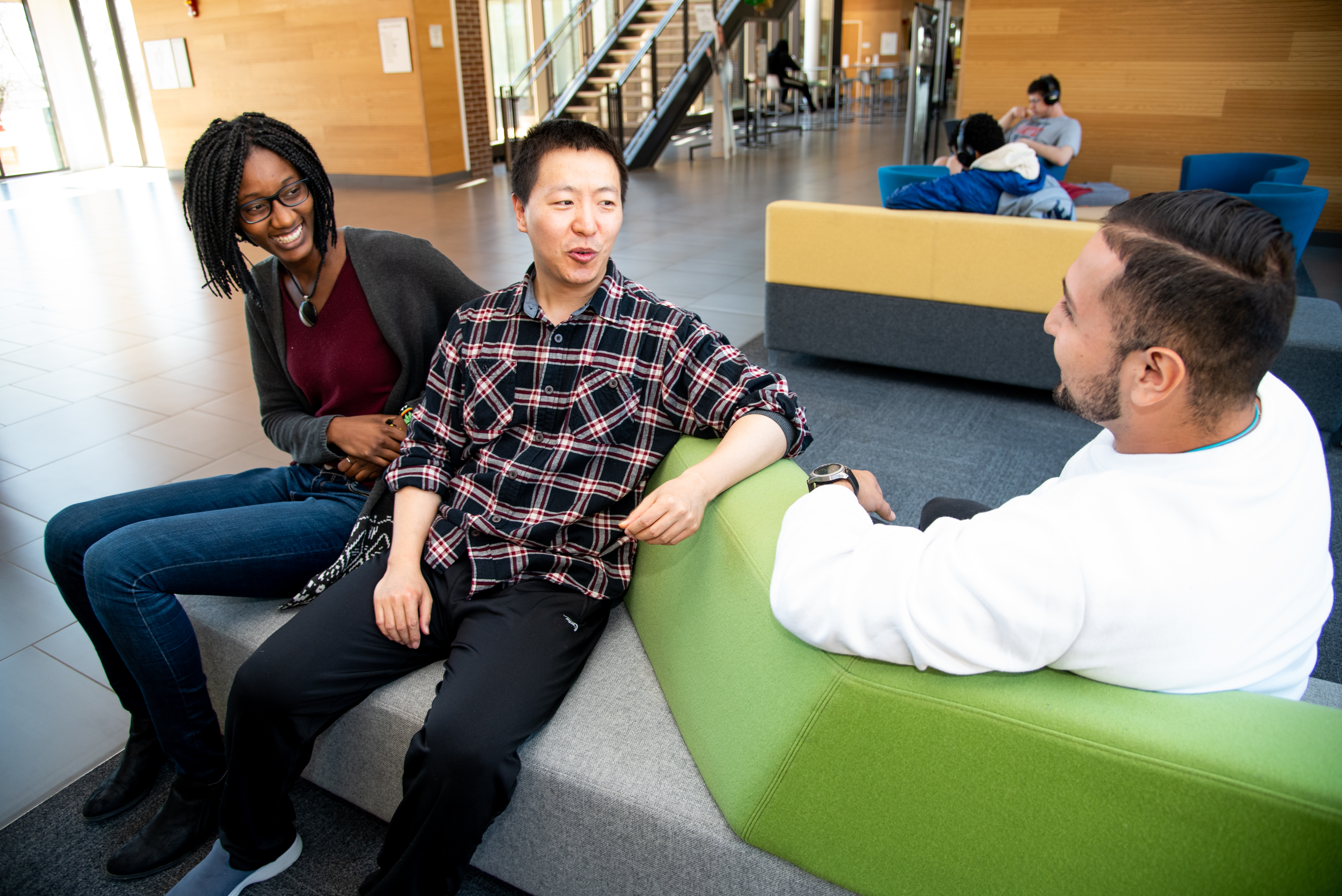 three racially diverse students speaking on student union couch